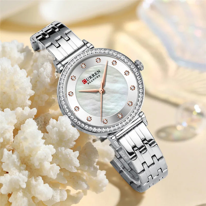 Stainless steel women's watch by Curren with a sleek round face and minimalist design, displayed on a white background.