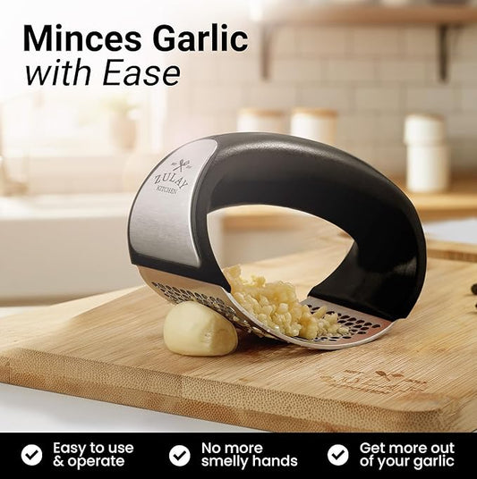 Stainless steel garlic crusher kitchen tool by Tarjah Mart, with textured handles and a chamber for crushing garlic cloves.